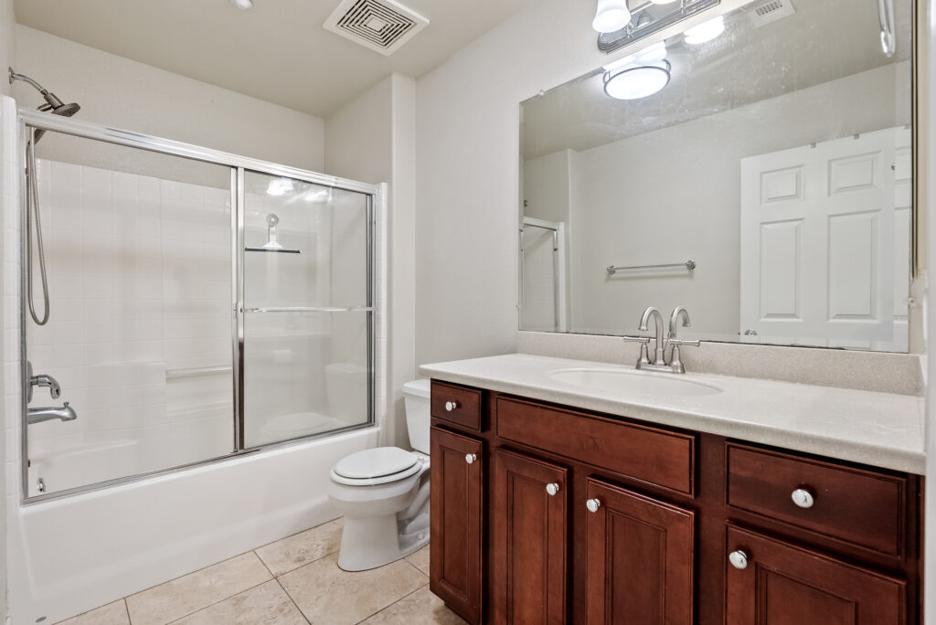 Full bathroom with large vanity, overhead lighting, and shower-tub combo