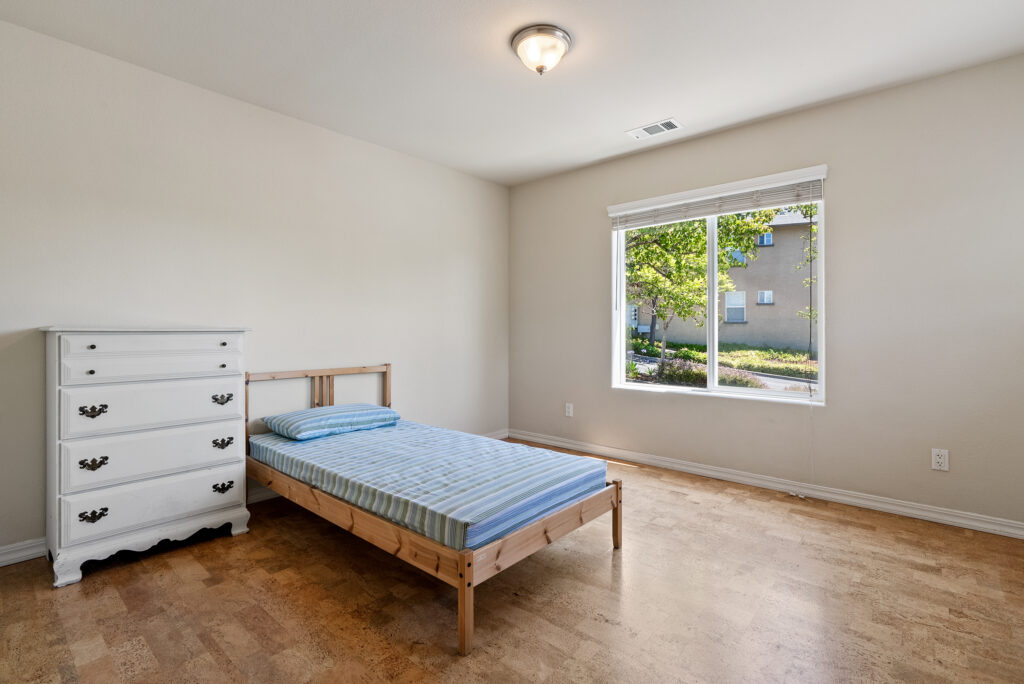Third bedroom with large window and view of landscaped exterior