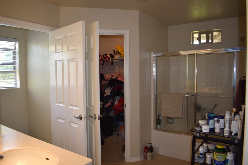 Full bathroom with dual sinks, glass-enclosed shower, and walk-in closet.
