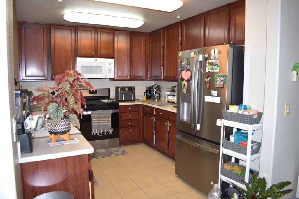 Updated kitchen with dark wood cabinets, stainless steel refrigerator, new stove and dishwasher, and ample counter space.
