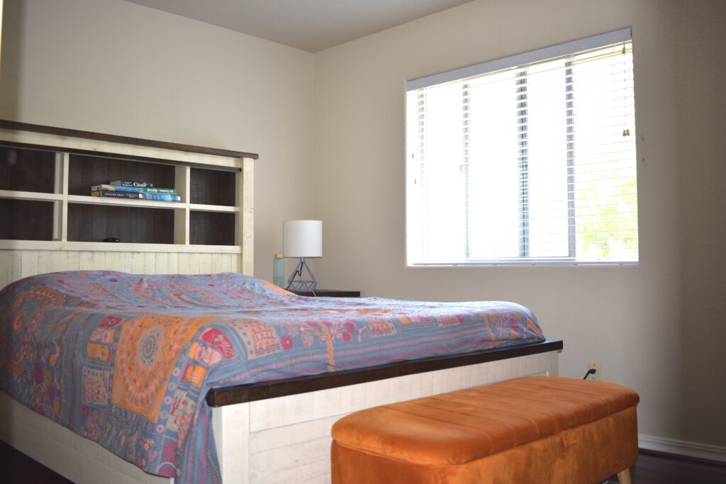 Second bedroom with twin bed, Pikachu pillow, colorful bedding, and bookshelf with toys and books.