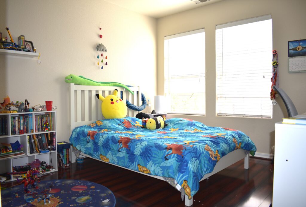 Primary bedroom with large window, built-in headboard shelving, and abundant natural light.