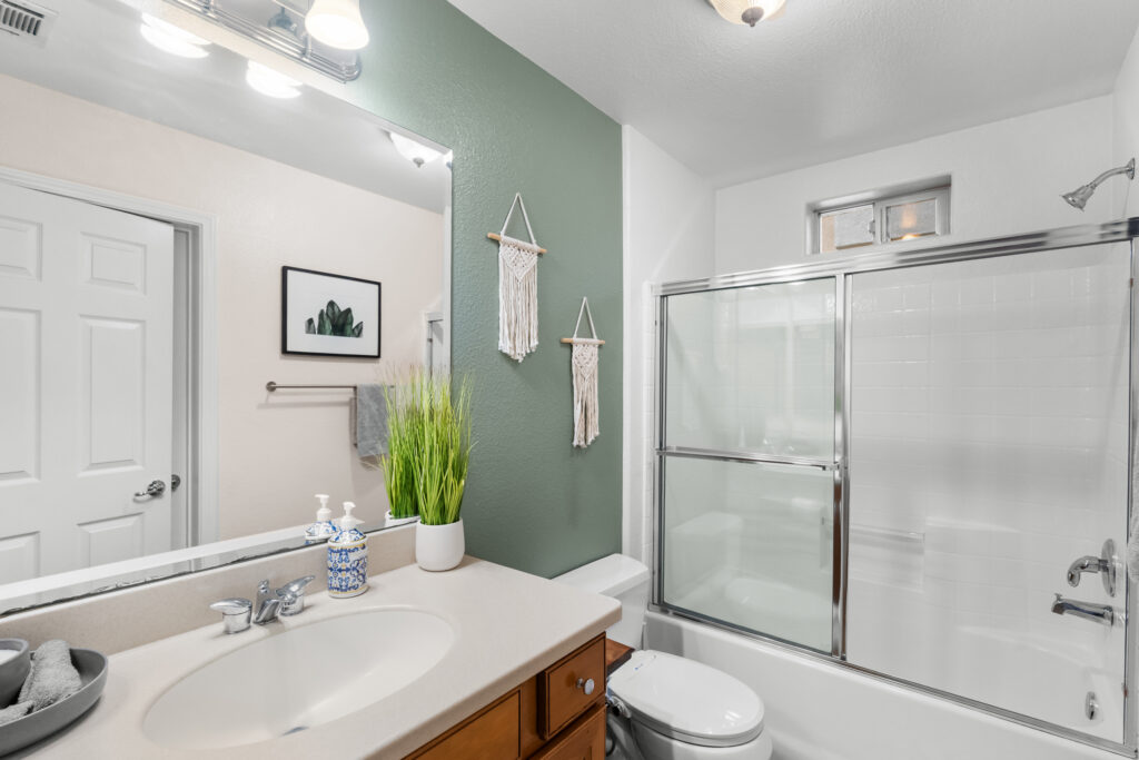 Bathroom with vanity, green accent wall, and glass-enclosed shower-tub combination at 545 Paseo Bella Montana.