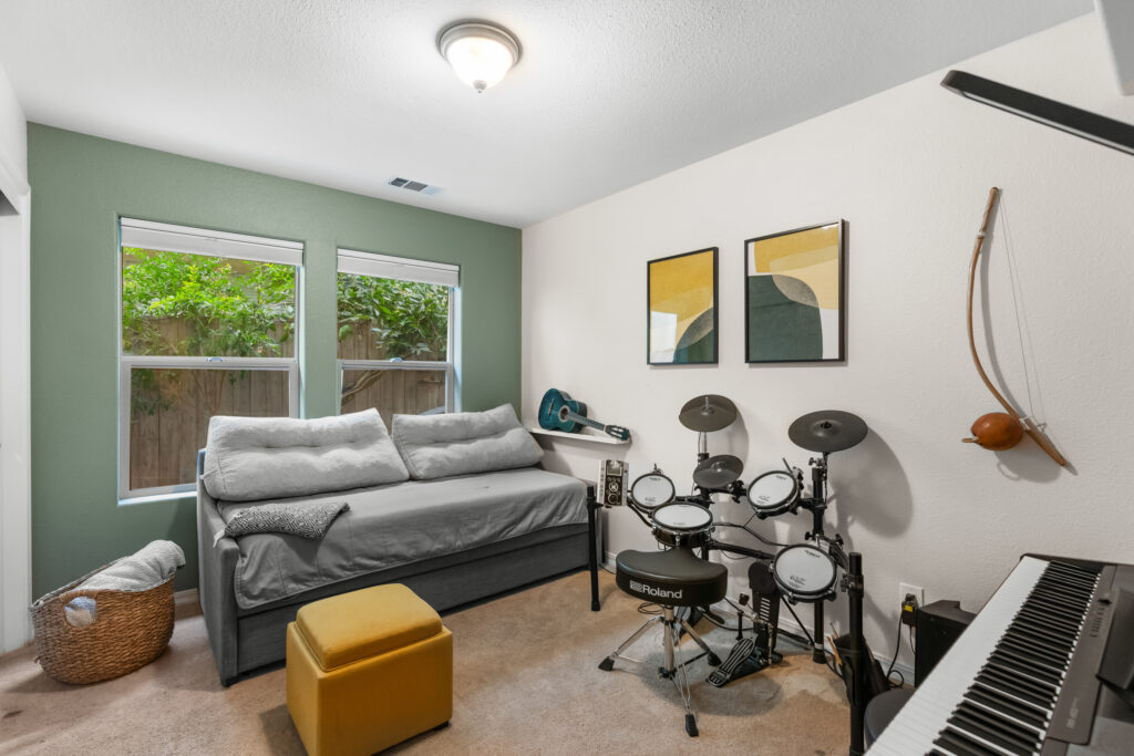 Guest bedroom with daybed, drum set, and green accent wall at 545 Paseo Bella Montana.