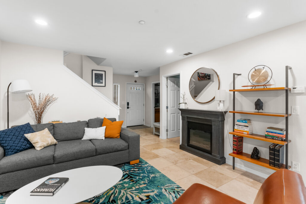 Living room with gray sofa, fireplace, wall mirror, and bookshelves at 545 Paseo Bella Montana.