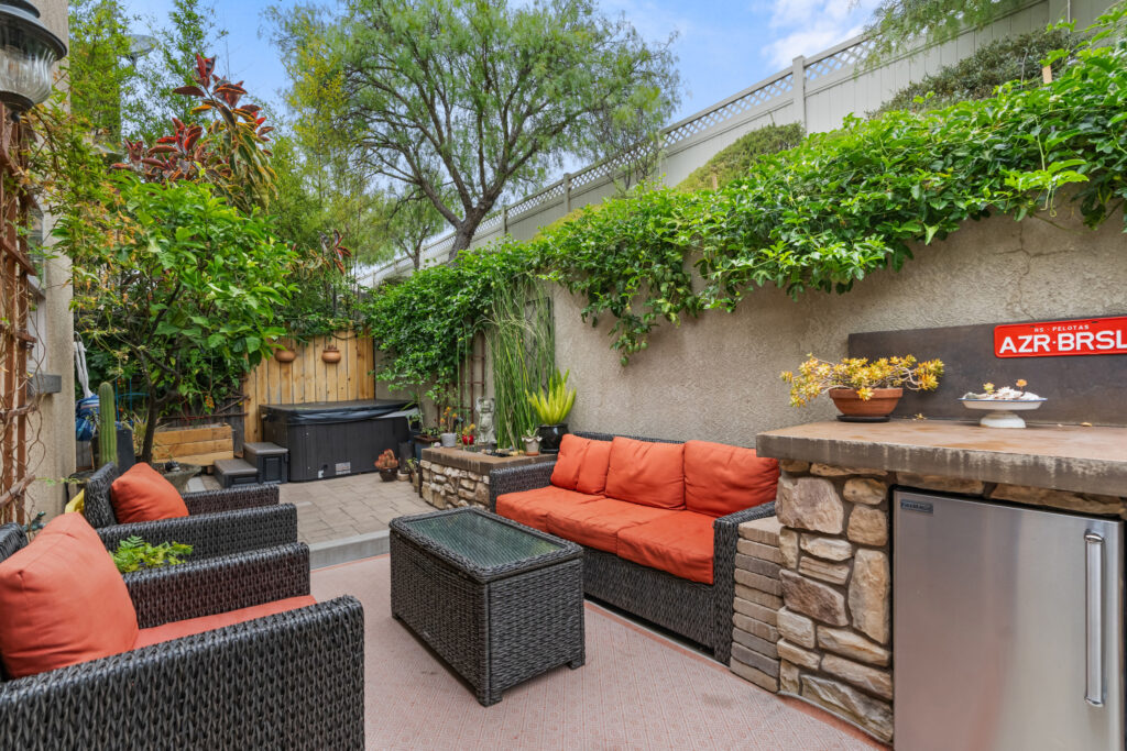 Private outdoor patio with wicker furniture, built-in counter, and lush greenery at 545 Paseo Bella Montana.